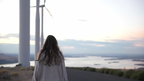 modelo caminando por debajo de los molinos de viento al atardecer en cámara lenta