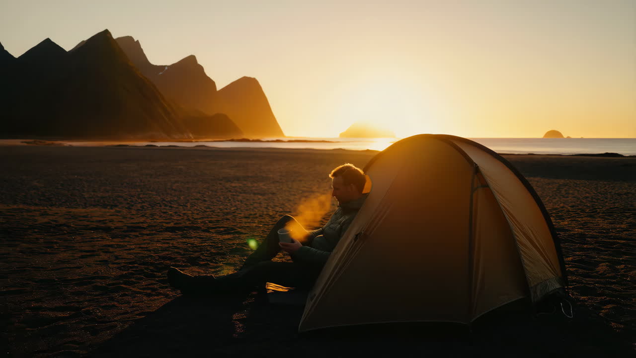 Man camping on a beach at sunrise or sunset with mountains in the background