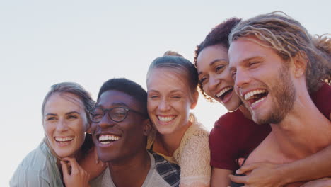 Männer-Nehmen-Frauen-Huckepack,-Während-Eine-Gruppe-Von-Freunden-In-Die-Gleißende-Sonne-Lächelt