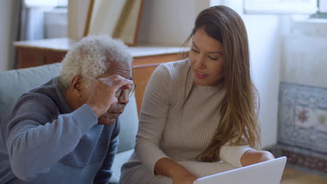 Pretty-Caucasian-girl-helping-senior-Black-man-with-using-laptop