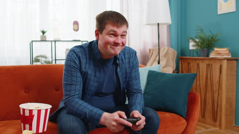 man using joystick controller playing console online video game fun enjoying sitting on home sofa