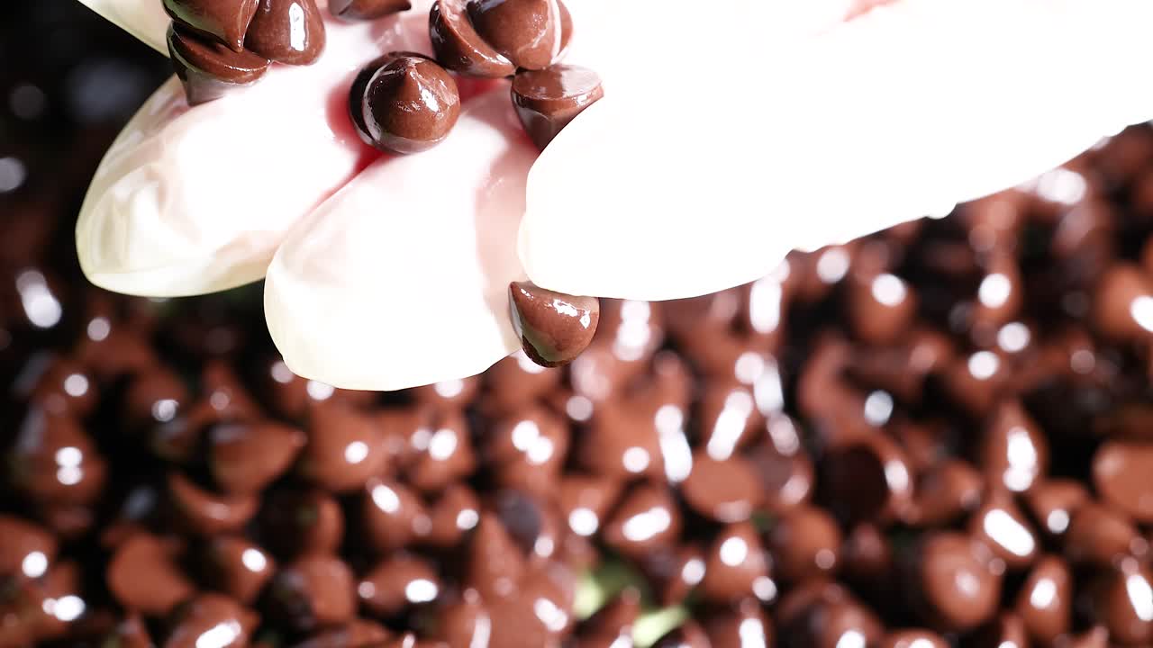 manos con guantes clasificando con cuidado las fichas de chocolate