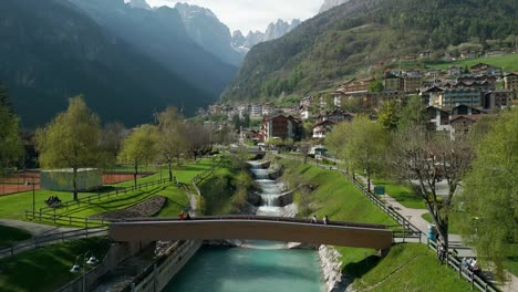 Fußgängerbrücke-über-Den-Bach-Mit-Bergen-Im-Hintergrund,-Molveno-In-Italien