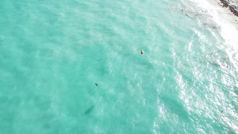 Capturas-Aéreas-De-Kitesurf-Deslizándose-Sobre-La-Superficie-Del-Agua-Del-Mar,-Energía-Eólica-Con-Una-Cometa-Eléctrica-Para-Tirar-De-Un-Ciclista-A-Través-Del-Agua,-Ubicación-Isla-Blanca,-México