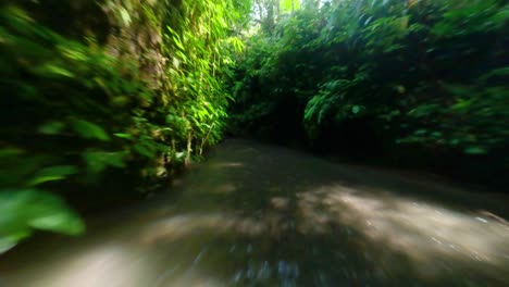 fpv drone shot over fast streaming river through caves while a blond woman is enjoying the water falling from the waterfall