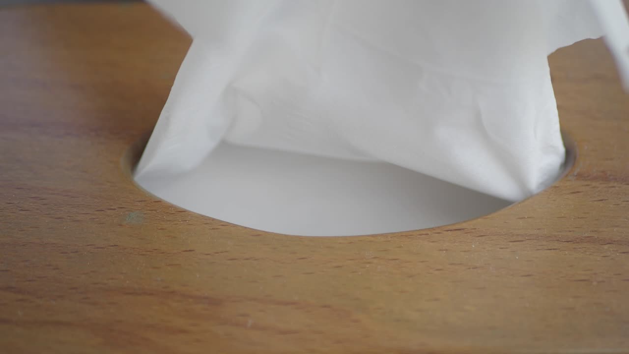 mano tomando un pañuelo de una caja de pañuelos