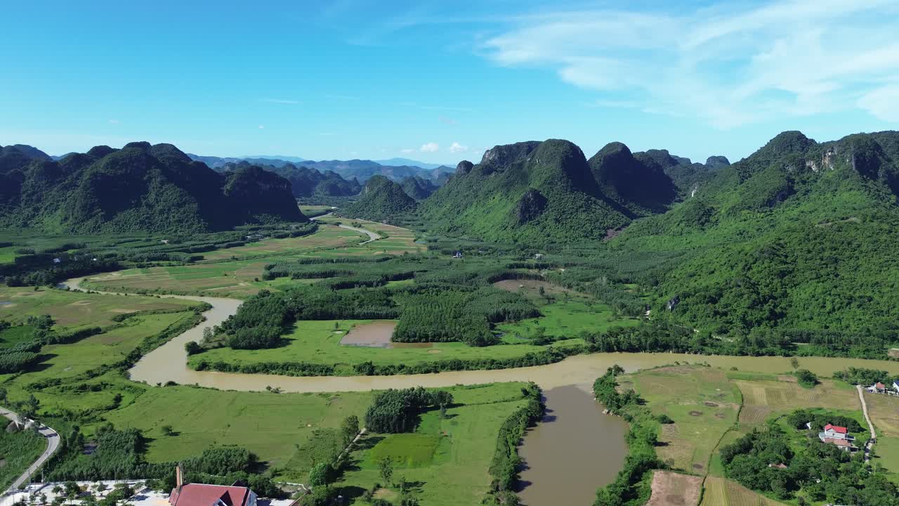 Zoom in over winding river and karst mountains under clear sky in Phong Nha, Vietnam