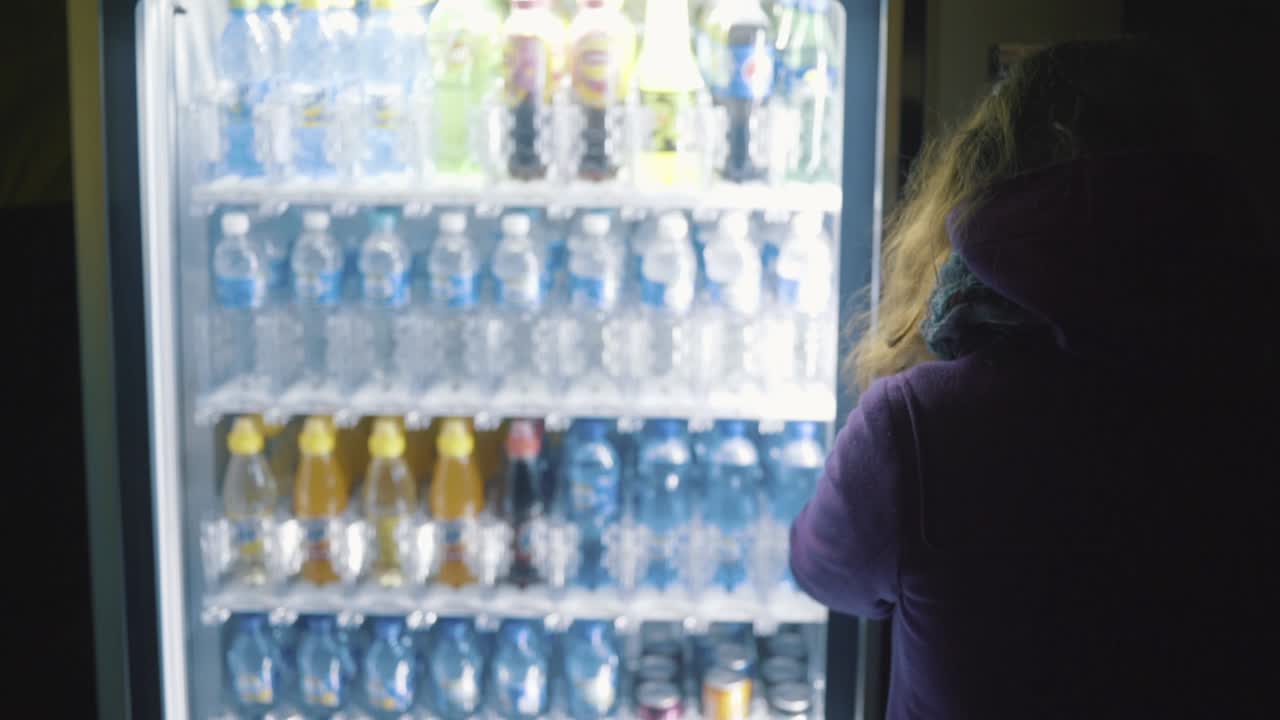 Persona che acquista bevande da un distributore automatico di notte