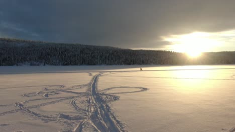 hermoso paisaje invernal con esquiadores en un lago congelado con puesta de sol y montañas al fondo
