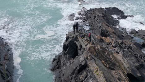 climbers on rocky coastline with powerful waves