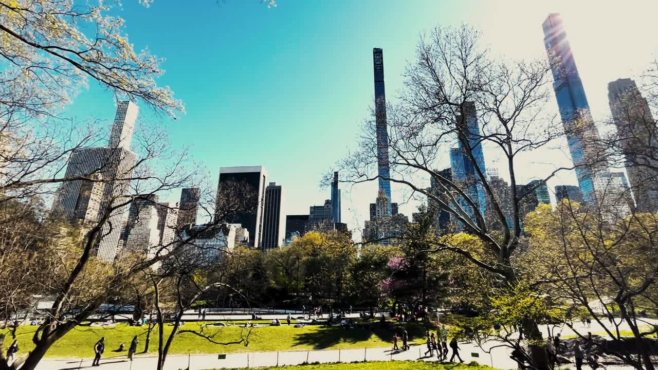 People enjoying themselves in Central Park in New York City with the Manhattan skyline in the background