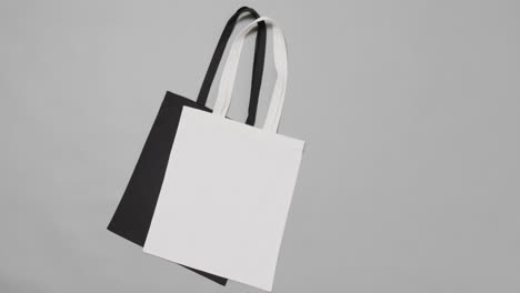 Close-up-of-white-and-black-bags-on-grey-background,-with-copy-space,-slow-motion