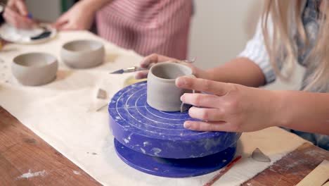 woman shaping a mug on a pottery wheel