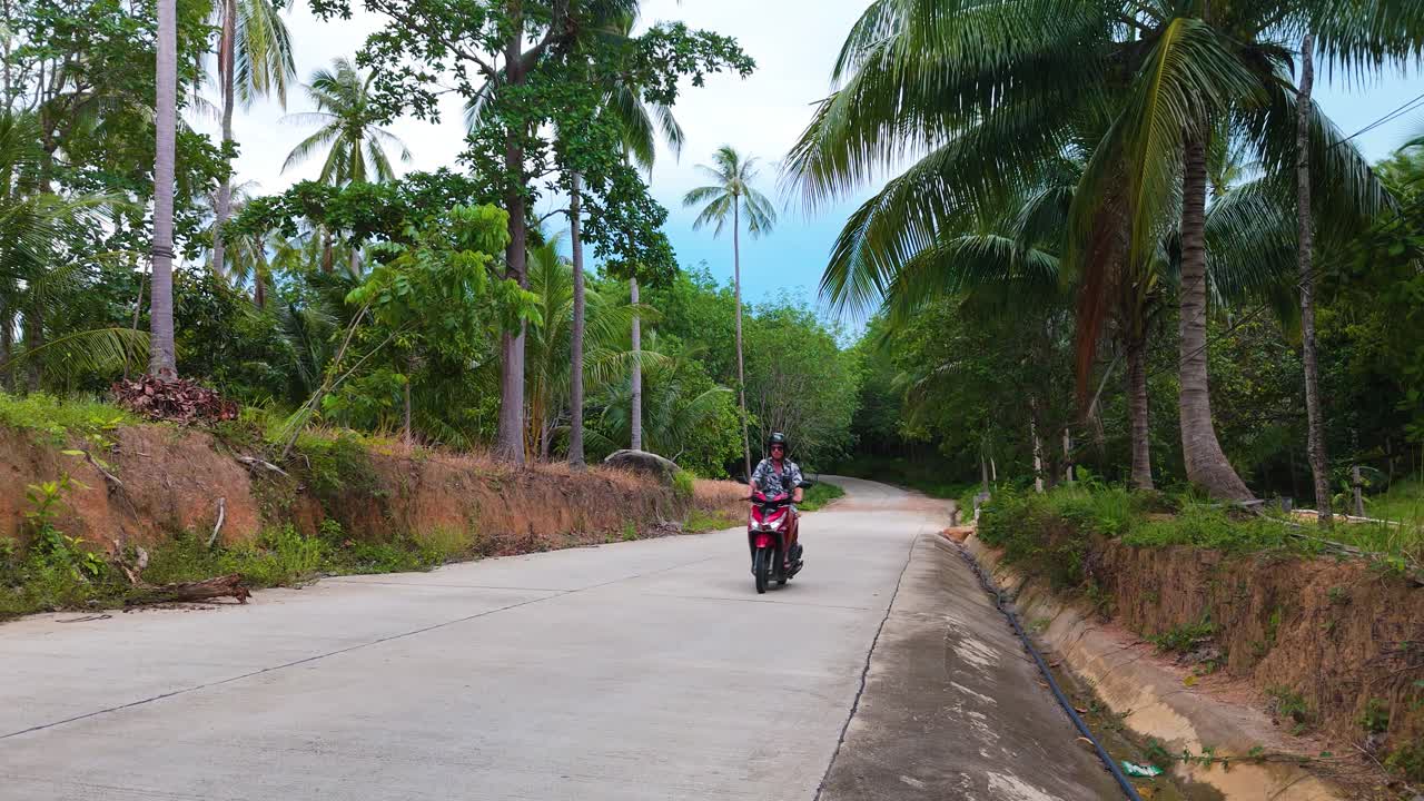 static view of thailand road, tourist on bright red moped, drives by, tourist thailand roadtrip in Ko Pha Ngan island peaceful scenery showing the holiday feeling