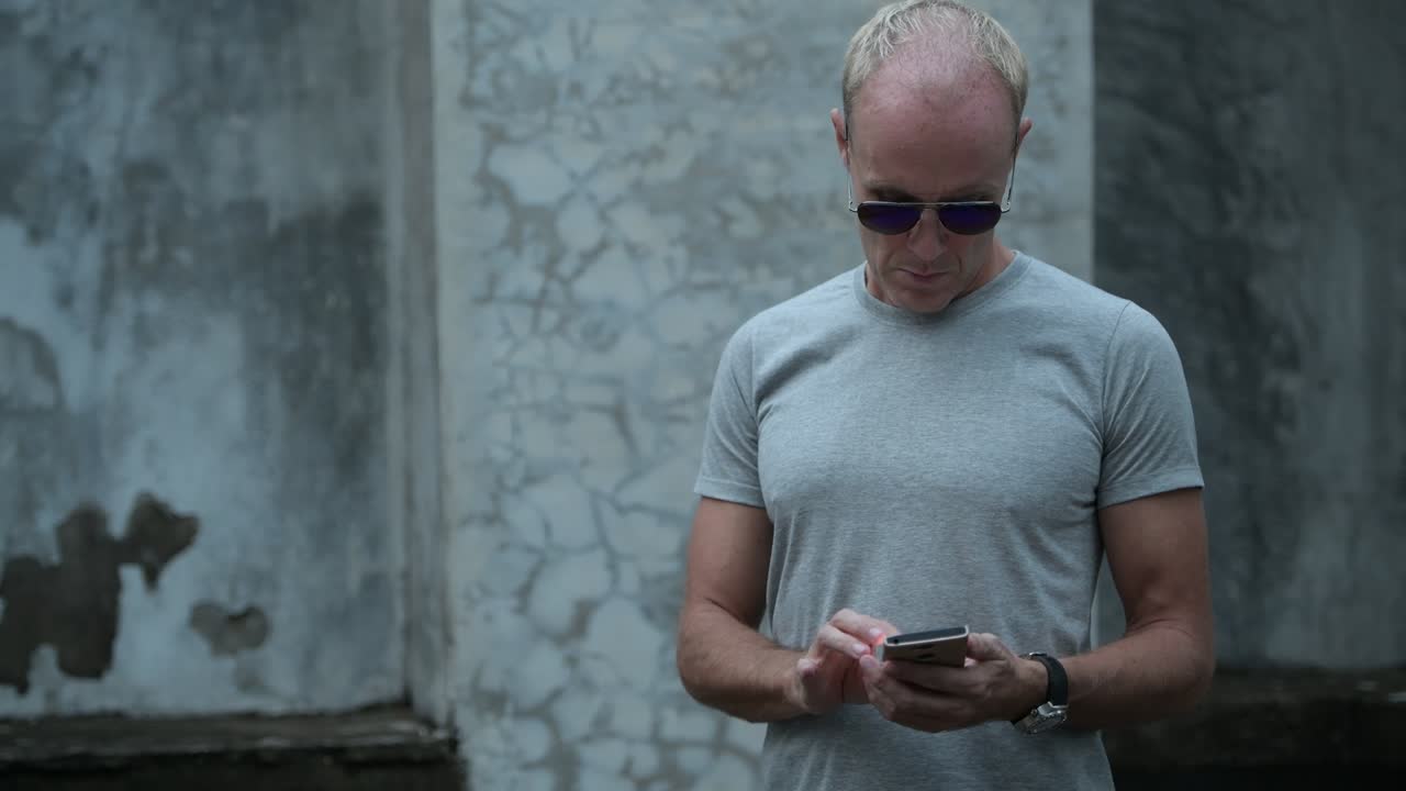 Uomo scandinavo maturo che usa il telefono con gli occhiali da sole
