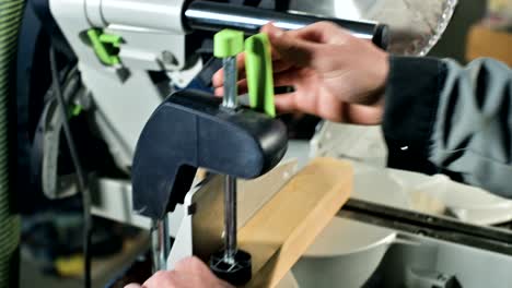 close up mans hands carpenter installs a wooden work piece in a circular sawing machine