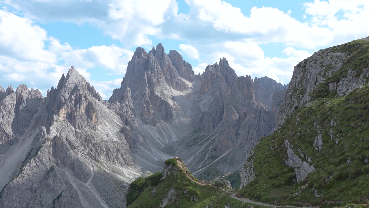 Vista panoramica di un escursionista presso l'iconico punto panoramico dei Cadini di Misurina, circondato dalle imponenti cime dolomitiche nel nord Italia.