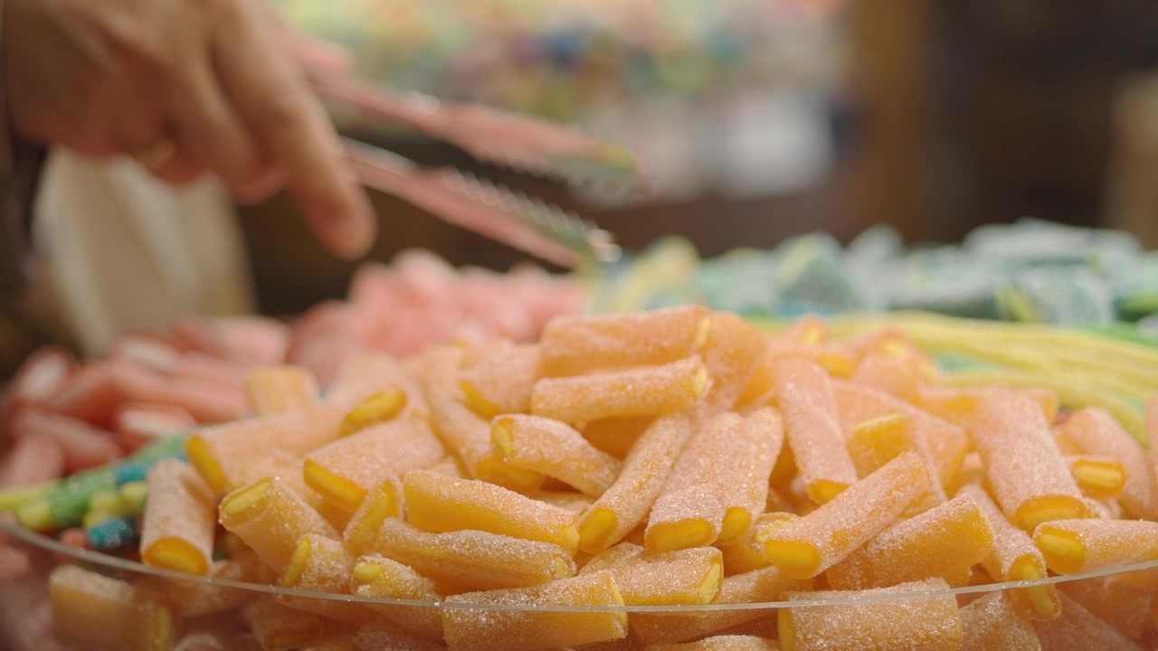 Persona che usa le pinze per selezionare caramelle gommose in un negozio