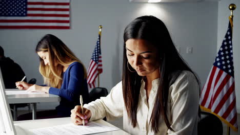 women filling out forms in a voting or exam setting