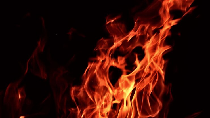 Fiamme rosse danzano nell'oscurità. Splendida vista ipnotica del falò in primo piano.