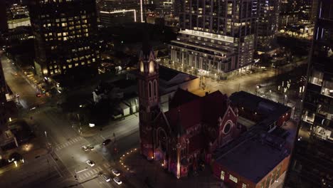 Aerial-view-of-an-ambulance-passing-by-a-church-at-night-in-Dallas,-Texas