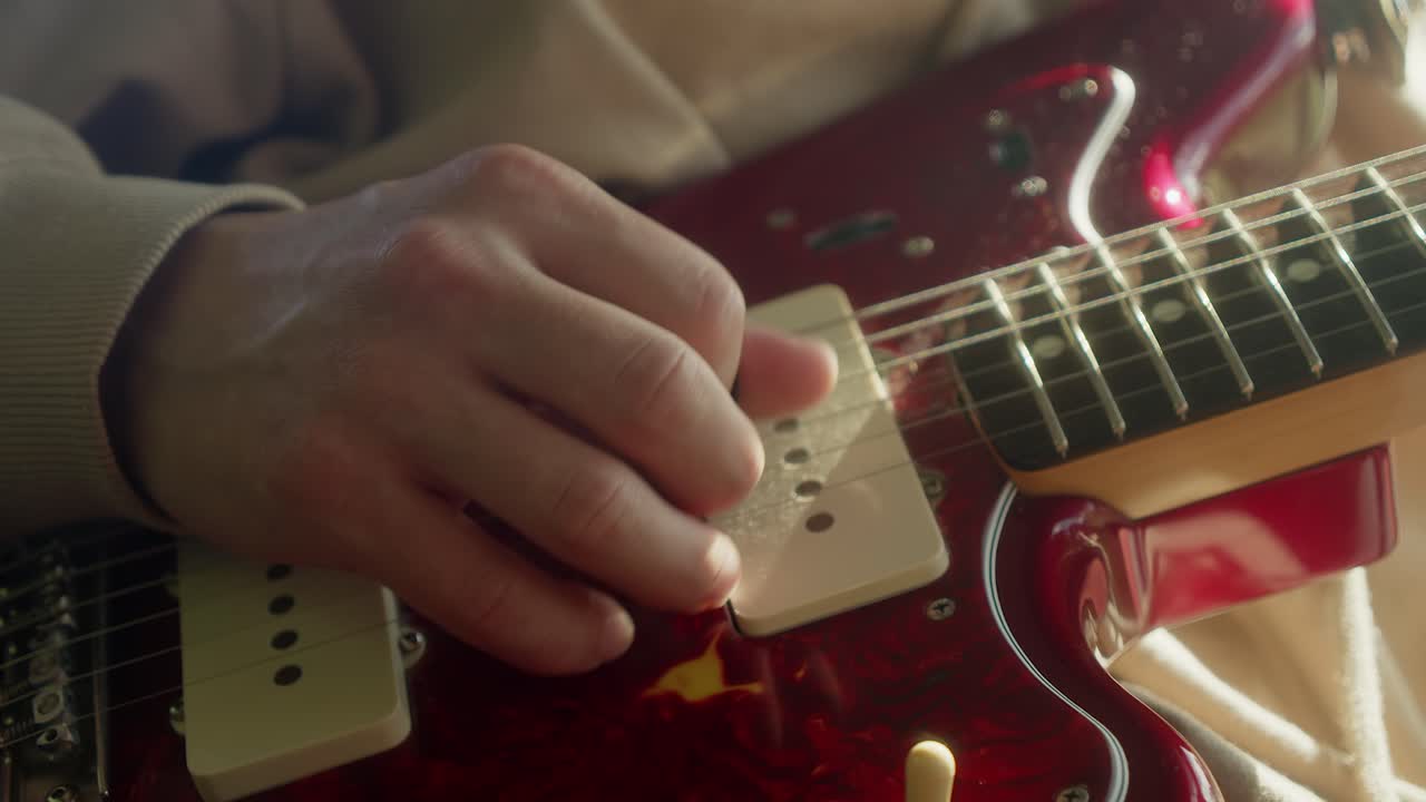 vista de cerca de la mano recogiendo guitarra eléctrica clásica de fender rojo jaguar