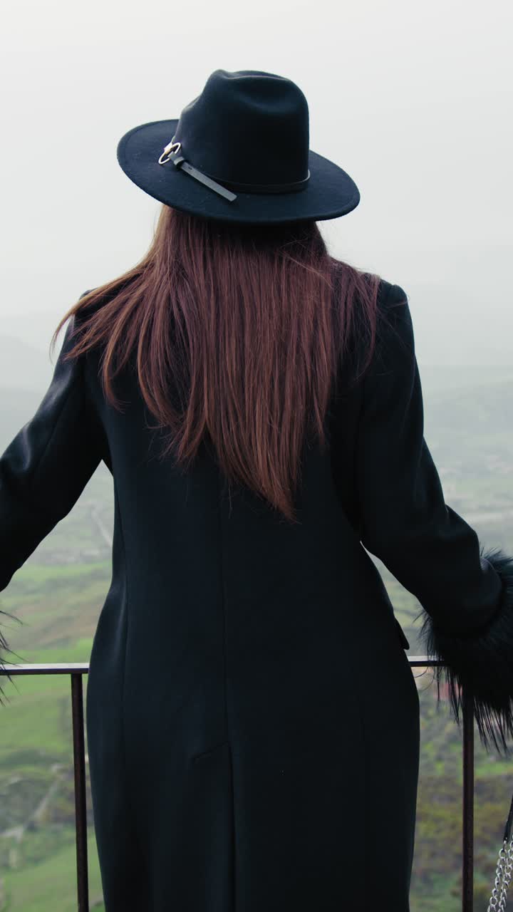 Woman Dressed In Black Coat Watching The Natural Landscape Down The Railing