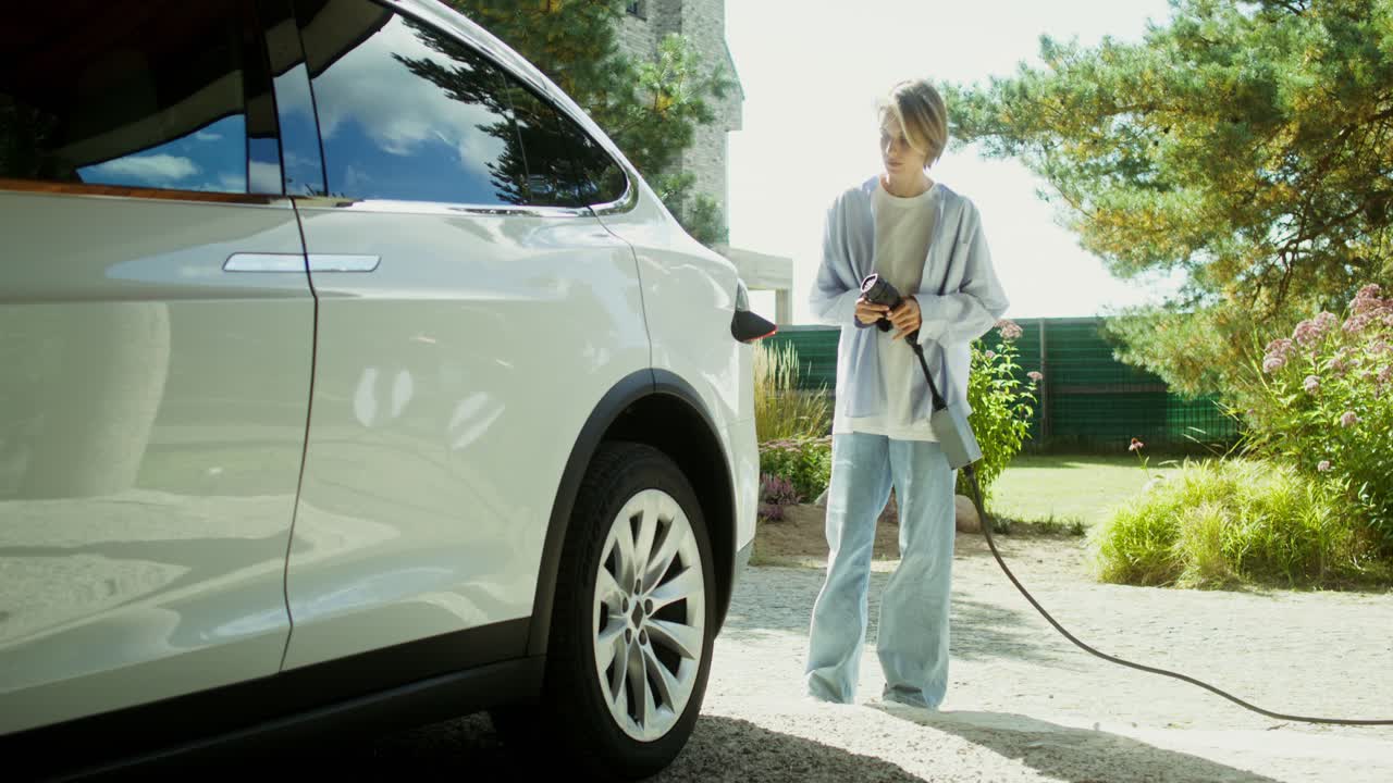 женщина заряжает электрический автомобиль дома