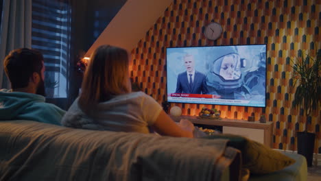 couple watching space news report on tv