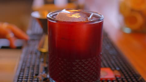 video de un trago de bayas con ginebra y arándanos servidos en un vaso golpeándolo con una cuchara de metal en un bar