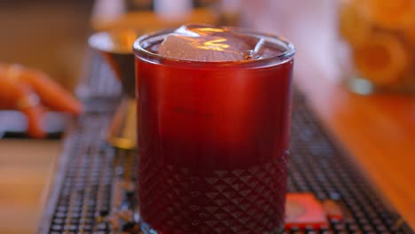 video eines schusses beeren mit gin und blaubeeren, serviert in einem glas, das mit einem metalllöffel in einer bar geschlagen wird