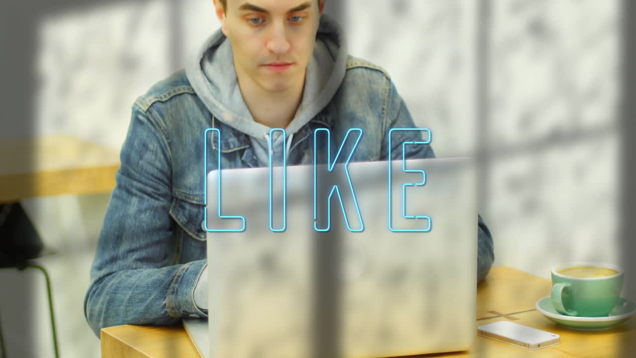 student working on laptop in café with phone and coffee showing neon-blue graphic for technology