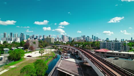 beautiful aerial of a train entering frame with miami skyscraper in background