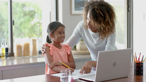 Glückliche-Biracial-Mutter-Und-Tochter-Mit-Laptop-Für-Schularbeiten-In-Der-Küche,-Zeitlupe