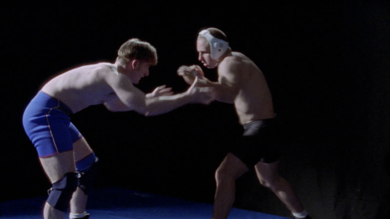 두 남자가 바닥에 있는 매트에서 레슬링을 하고 있다