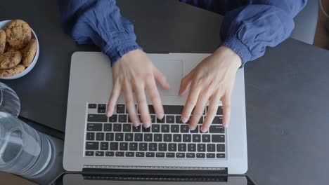 Manos-Femeninas-Escribiendo-En-El-Teclado-De-Una-Computadora-Portátil,-Vista-De-Arriba-Hacia-Abajo