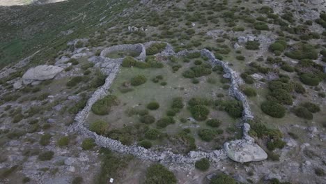 flight in retreat and ascent with a drone visualizing a closed stone enclosure with 2 attached structures used for livestock and previously for bullfighting celebration events until the 17th century