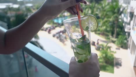 la fille remue lentement un mojito doux et froid avec une longue paille en plastique