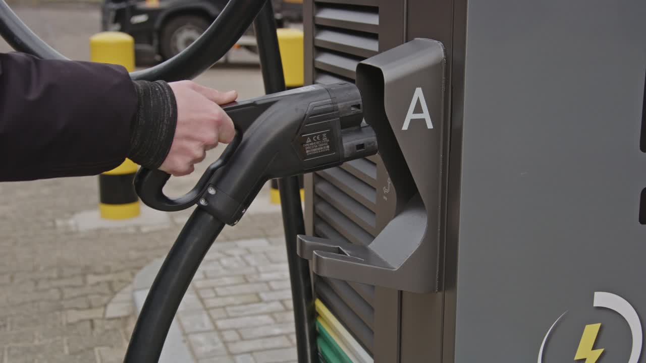 Hand placing the plug of an EV charging station back into the large station in slow motion