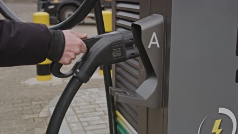 Hand placing the plug of an EV charging station back into the large station in slow motion
