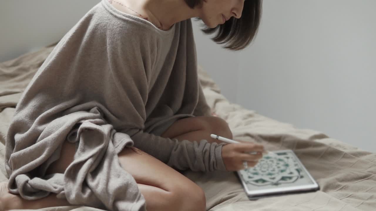 침대에서 태블릿에 그림을 그리는 여자