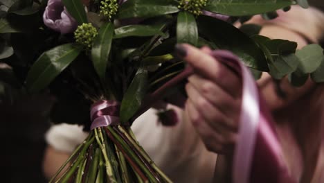 el ramo se recoge de varios tipos de flores. el florista decora los tallos con una cinta decorativa. niña florista en el fondo