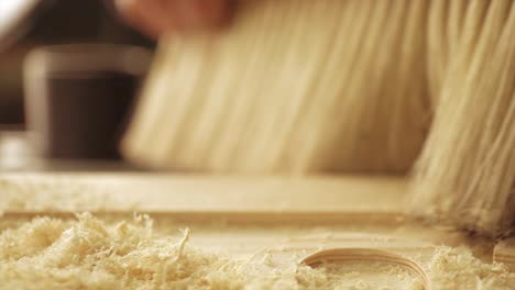 a slow motion macro shot of a carpenter brushing sawdust from a timber sign