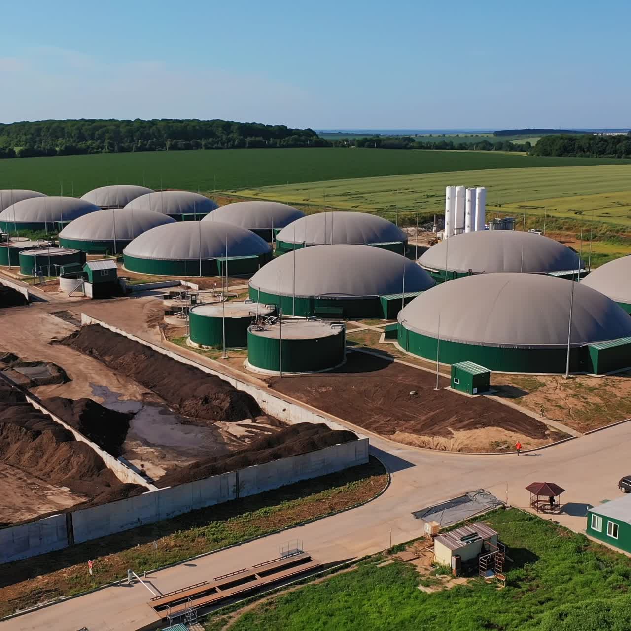 Big round storage tanks for biogas production. Innovative plant for turning garbage into energy. Agricultural fields at the backdrop