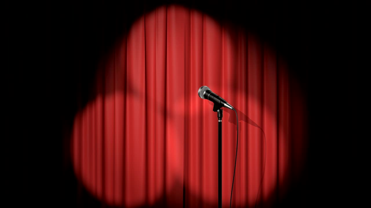 스포트라이트와 마이크를 가진 은 커튼으로 무대 위에 서