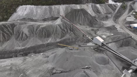 coneyor belt and machinery around massive piles of sand and crushed rock at visnes mining site close to molde norway