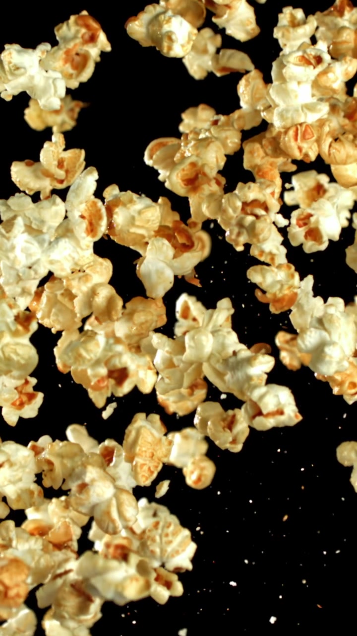 Deliziosi popcorn al caramello che volano al rallentatore su sfondo nero