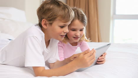 smiling siblings touching a tablet computer