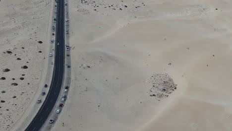 cars line tow lane highway road in middle of sand dunes at corralejo beach, aerial fuerteventura