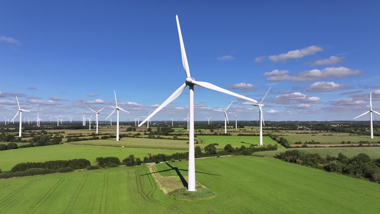 Wind turbines farming wind energy, green fields, blue sky, countryside, sunny, slow drone orbit, green sustainable power
